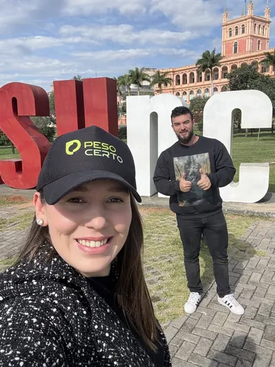 Pâmela de boné em primeiro plano e Samuel ao fundo, com o Palacio de los López atrás, em Assunção