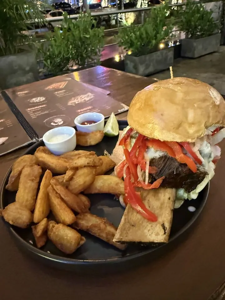 Hambúrguer com batatas rústicas em uma mesa ao ar livre