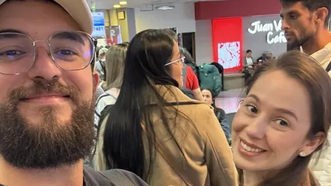 Samuel e Pâmela em uma selfie sorridente dentro de uma repartição pública cheia de gente