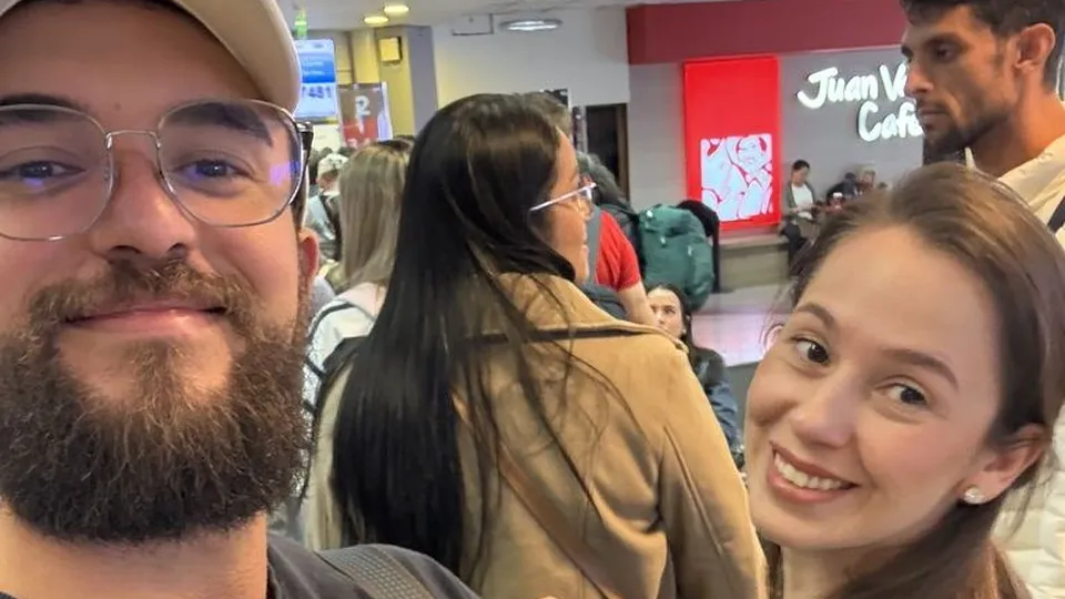 Samuel e Pâmela em uma selfie sorridente dentro de uma repartição pública cheia de gente