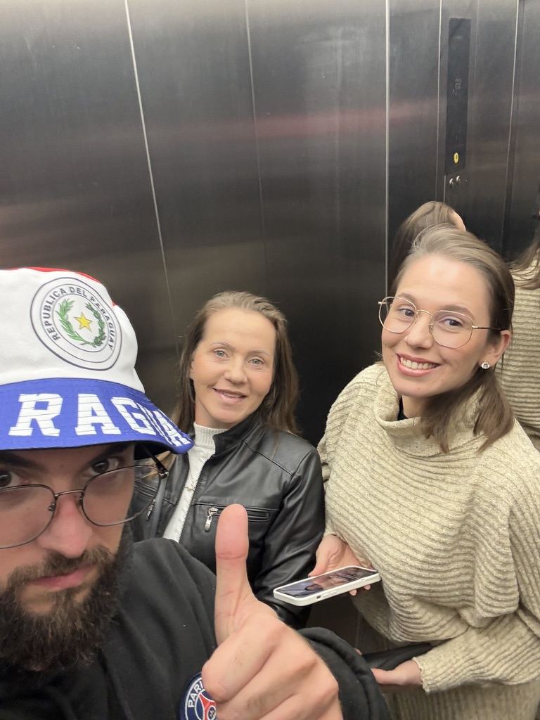 Selfie no elevador: ele de boné com a palavra Paraguay, ao lado de duas mulheres sorrindo