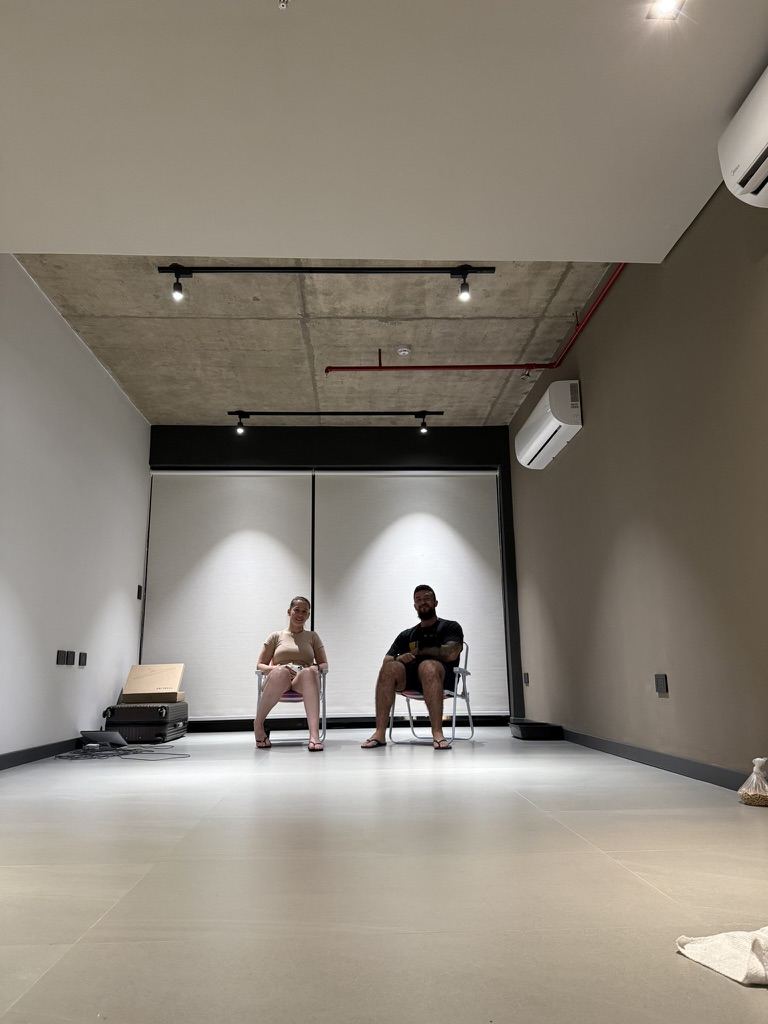 Duas pessoas conversando sentadas em uma sala ampla e clara